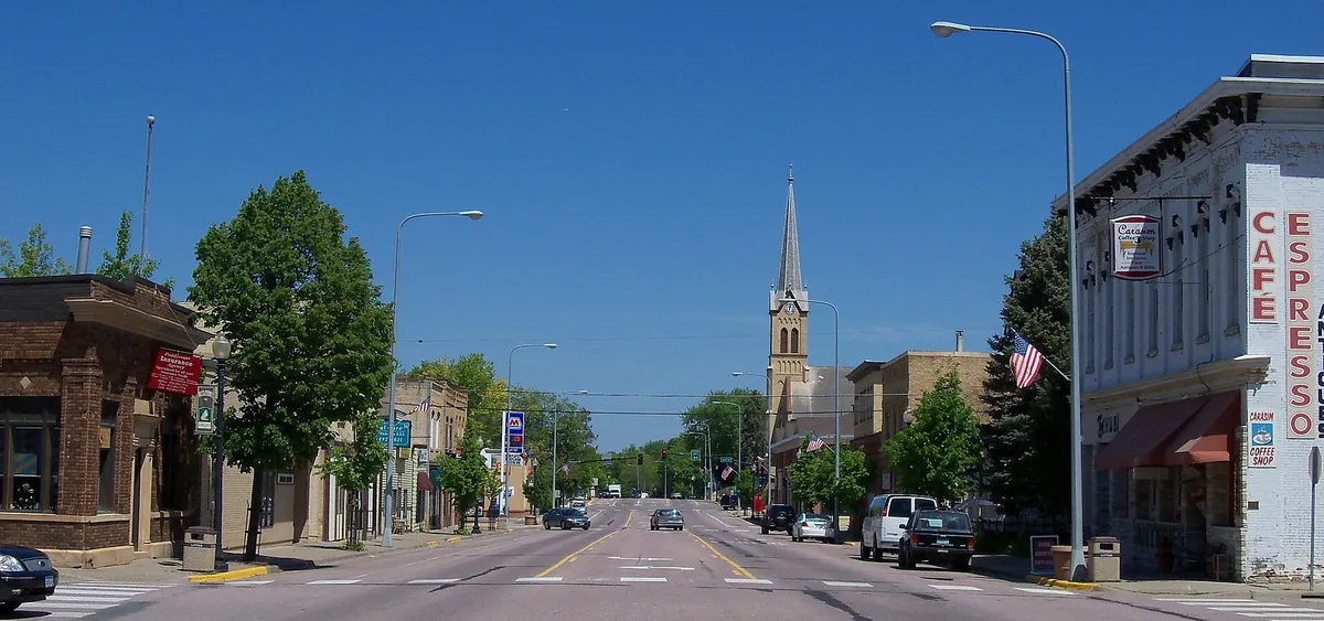 Jordan’s main street on a clear day, historic brick storefronts on both sides and a tall church spire beyond